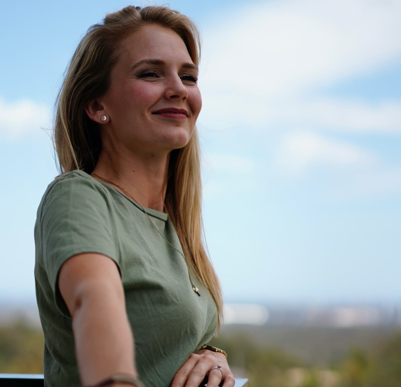 Denise outdoors against an open sky, smiling and looking out
